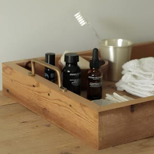 Close-up view of a handcrafted solid brass pull handle held in hand, showing texture and mounting hole.