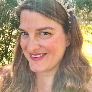 May include: A woman wearing a crystal headband with clear quartz points and a silver chain necklace with a purple crystal pendant.