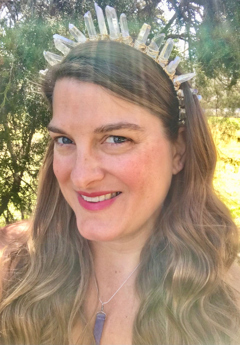 May include: A woman wearing a crystal headband with clear quartz points and a silver chain necklace with a purple crystal pendant.