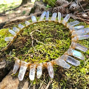 May include: A gold wire headband with iridescent clear quartz crystals wrapped around it. The headband is lying on a bed of green moss.