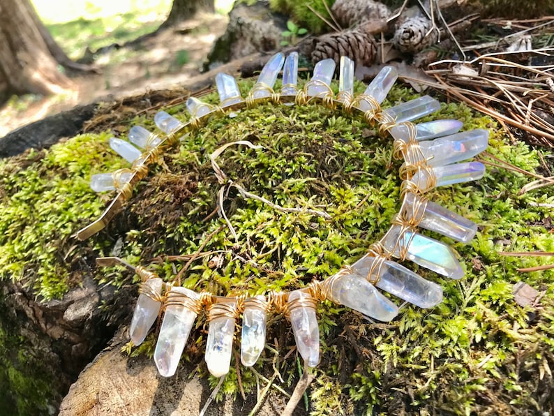 May include: A gold wire headband with iridescent clear quartz crystals wrapped around it. The headband is lying on a bed of green moss.