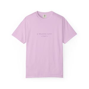May include: A pale lilac t-shirt with short sleeves. The shirt displays the text "for the first time in forever" in a cursive font, with a decorative line beneath. It has a crew neck and a label at the back of the neck.