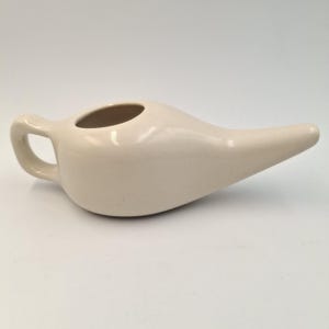 Könnte beinhalten: Set aus drei Keramikbechern mit gesprenkelter, matter Oberfläche. Die Becher sind in Creme-, Hellgrau- und Dunkelgrautönen gehalten. Schlichtes, minimalistisches Design.