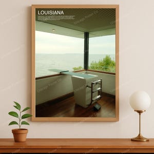 Pode incluir: Uma impressão emoldurada com a palavra "LOUISIANA" no topo, mostrando um design arquitetônico moderno. A imagem mostra uma prancha de mergulho e uma piscina brancas com vista para a água. A impressão está em uma moldura de madeira.