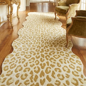 May include: A cream-coloured rug with a leopard print pattern in shades of gold and tan. The rug has an irregular shape and is on a wooden floor. The room features antique furniture and decor.