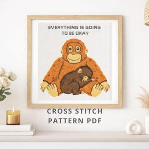 May include: A framed cross-stitch pattern featuring an orangutan and baby. The orangutan is orange and the baby is brown. The text "EVERYTHING IS GOING TO BE OKAY" is above the orangutan. The words "CROSS STITCH PATTERN PDF" are below.