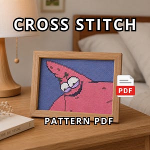 Könnte beinhalten: Ein Kreuzstichmuster-PDF mit einem verpixelten Bild einer rosa Seesternfigur mit großen Augen und einem breiten Lächeln vor violettem Hintergrund, präsentiert in einem hellen Holzrahmen mit dem Text CROSS STITCH PATTERN PDF.