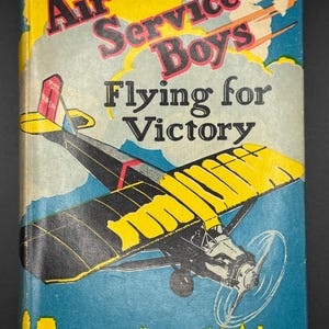 May include: Vintage book cover for "Air Service Boys Flying for Victory" by Charles Amory Beach. The cover features a yellow and black airplane illustration against a blue sky and cityscape background. The title is in bold red and black letters.