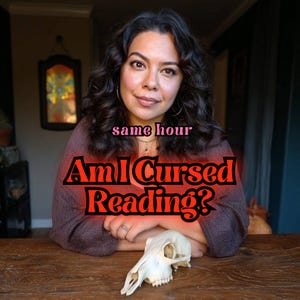 May include: A woman with dark curly hair and a brown top, with the text "same hour" and "Am I Cursed Reading?" in red. A white animal skull rests on a wooden table.