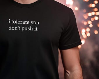 Puede incluir: Camiseta negra con el texto blanco "i tolerate you don't push it". La camiseta está hecha de un material suave y tiene cuello redondo. El texto está centrado en el pecho.