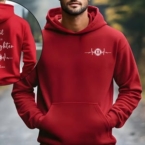 May include: A red hooded sweatshirt with a front pocket. It has a white graphic of a firefighter's emblem and heartbeat on the front. The back of the hoodie has the text "I am vital, yes I'm a Firefighter, you're awesome."