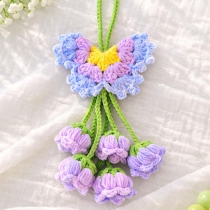 Puede incluir: Adorno floral hecho a mano con ganchillo. Presenta una parte superior en forma de mariposa en azul, morado y amarillo, con tallos verdes y capullos de flores lavanda. El adorno est&aacute; dise&ntilde;ado con un lazo para colgar.