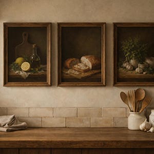 Può includere: Tre dipinti incorniciati di nature morte raffiguranti scene di cucina. Uno mostra un limone, olio d'oliva ed erbe. Un altro presenta pane a fette. Il terzo mostra aglio ed erbe. Utensili di legno e un barattolo di sale sul bancone.