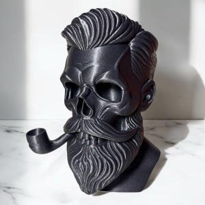 May include: A black skull bust with a beard and mustache, holding a pipe. The skull has a detailed hairstyle and is set against a white background. The bust is a unique decorative item.