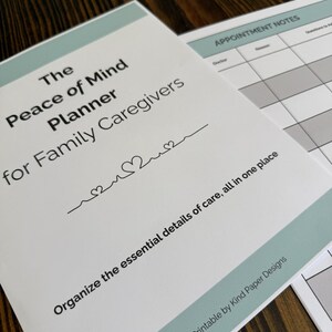 May include: A white planner titled "The Peace of Mind Planner for Family Caregivers" with a teal border. The planner includes the text "Organize the essential details of care, all in one place" and "A Printable by Kind Paper Designs."