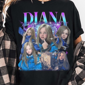 May include: Black t-shirt featuring the name "DIANA" in a vibrant, multi-colored font. The shirt showcases a collage of images of a person in a blue jacket. The design includes lightning bolt graphics, creating a retro aesthetic.