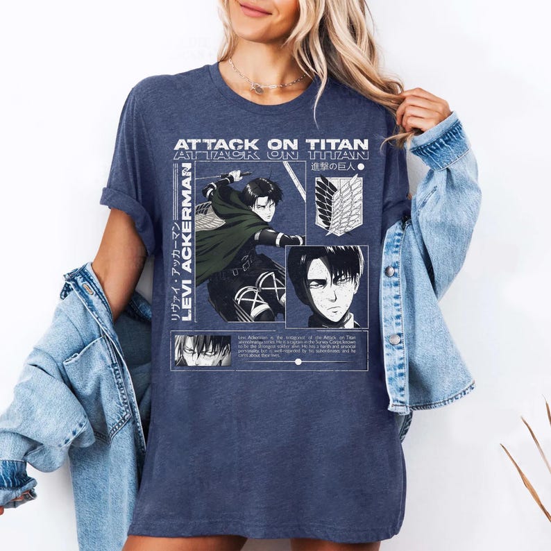 Pu&ograve; includere: Una maglietta blu navy con grafica della serie anime "Attack on Titan". Il design include il testo "Attack on Titan" e "Levi Ackerman" insieme a illustrazioni di personaggi in bianco. &Egrave; un capo di abbigliamento casual.