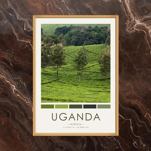 May include: A framed print featuring a vibrant landscape of Uganda. The image showcases lush green fields and trees, with a color palette strip at the bottom. The word "UGANDA" is displayed in a clean font, along with geographical coordinates.