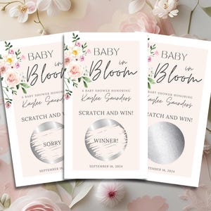 Könnte beinhalten: Babyparty-Rubbelkarten mit floralem Design. Die Karten zeigen den Text "Baby in Bloom" und "Scratch and Win!" mit einer "Sorry"- oder "Winner!"-Enthüllung. Die Karten sind hellrosa mit floralen Akzenten.