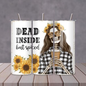 Może przedstawiać: Biały kubek z napisem "DEAD INSIDE but spiced" i ilustracją szkieletu w okularach przeciwsłonecznych i wianku ze słoneczników. Szkielet trzyma filiżankę kawy. Na kubku są słoneczniki.
