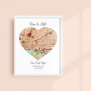 May include: A white framed print with a heart-shaped map of London, UK. The text "Drew & Matt" is at the top of the print. Below the map, the text reads "Our First Date, LONDON, UK, 8.26.2014."