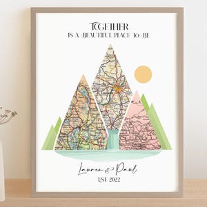 May include: A printable art print with a map design. The print features three mountains made of vintage maps with a sun and the text "Together is a beautiful place to be". The names "Lauren & Paul" and the date "Est. 2022" are written below the mountains.