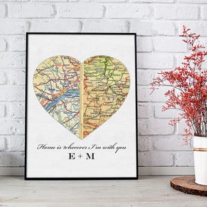 May include: A framed print with a heart-shaped map design. The map is divided into two halves, each with a different location. The text below the map reads "Home is wherever I'm with you E + M".