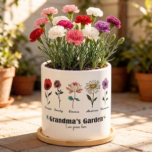 May include: A white ceramic planter with a variety of colorful carnations. The planter is decorated with floral illustrations and the text "Grandma's Garden" and "Love grows here". The planter sits on a wooden tray.
