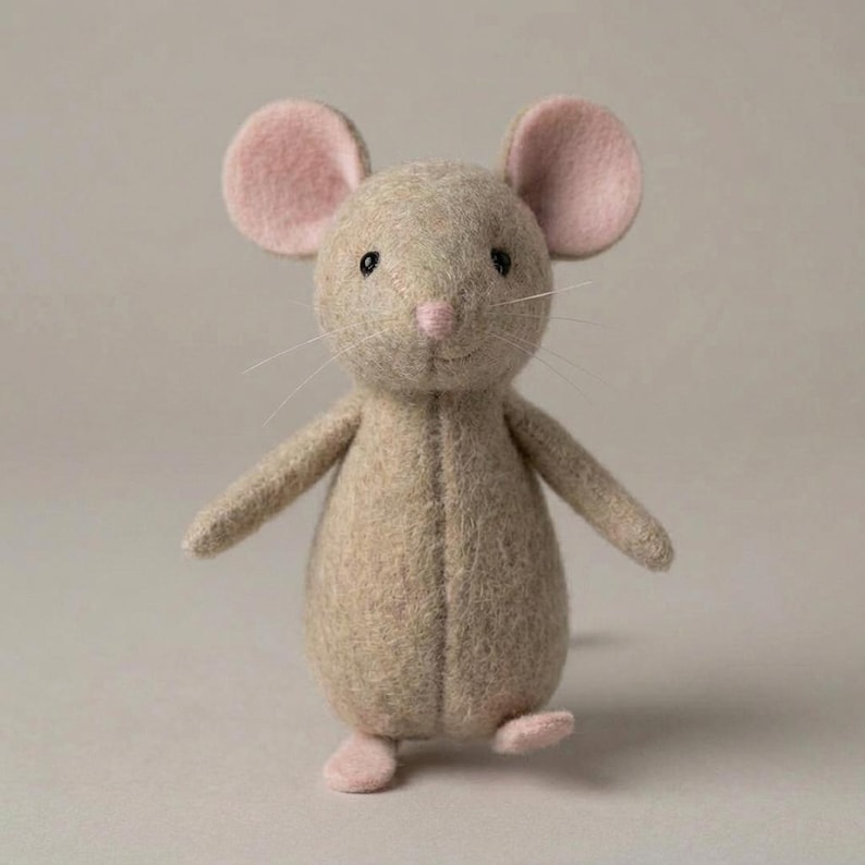 May include: A handmade stuffed mouse toy in a standing pose. The mouse is made of beige felt with pink felt ears, nose, and feet. It has black bead eyes and white whiskers. The toy is designed to be a decorative item or a child's toy.