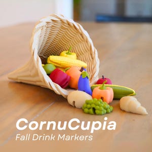 May include: A wicker cornucopia spilling out miniature fruits and vegetables in various colours. The display includes yellow corn, red apples, orange pumpkins, and green grapes. The text "CornuCupia Fall Drink Markers" is displayed below the cornucopia.