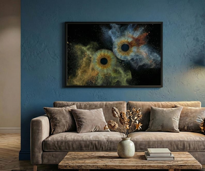 May include: A rectangular wall art print in a black frame featuring two human irises centered against a black background, surrounded by swirling clouds of gold and blue dust particles that create a vibrant, explosive visual effect.