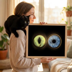 May include: A framed print featuring two glowing eye illustrations. One eye is green with a slit pupil, the other is blue with a round pupil. The artwork is set against a black background and framed in wood.