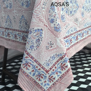 May include: A white tablecloth with a paisley pattern in shades of blue and red. The border features a striped design. The text "AQSA'S" is visible on the tablecloth.