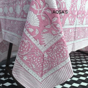 Könnte beinhalten: Rosa Tischdecke mit weißem Blumenmuster und Bordüre. Die Tischdecke hat ein sich wiederholendes Blumendesign mit Blättern und Blüten. Der Rand hat ein Streifenmuster. Der Text "AQSA'S" ist in der oberen rechten Ecke sichtbar.