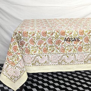 K&ouml;nnte beinhalten: Blumen-Tischdecke mit einem sich wiederholenden Muster aus rosa Bl&uuml;ten und gr&uuml;nen Bl&auml;ttern auf wei&szlig;em Hintergrund. Der Rand hat ein detailliertes Blumendesign. Der Text "AQSA'S" ist auf der Tischdecke zu sehen.