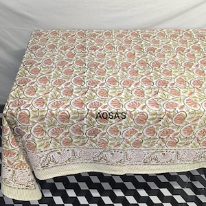 K&ouml;nnte beinhalten: Eine Steppdecke mit floralem Muster mit wei&szlig;em Hintergrund und rosa und gr&uuml;nen Blumen. Die Steppdecke hat einen Rand mit einem &auml;hnlichen floralen Design. Der Text "AQSA'S" ist auf die Steppdecke gedruckt.