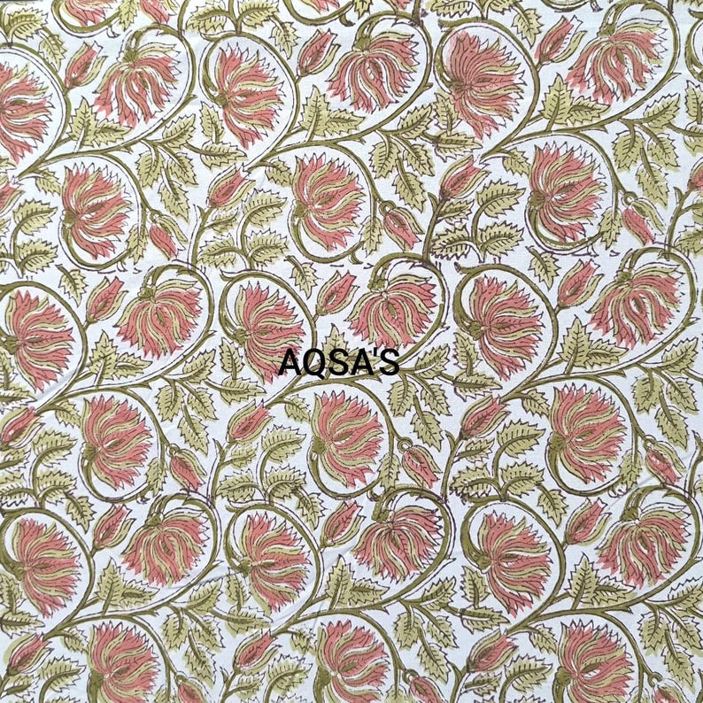 K&ouml;nnte beinhalten: Wei&szlig;er Stoff mit einem sich wiederholenden Blumenmuster. Die Bl&uuml;ten sind zartrosa mit gelben Zentren, die Bl&auml;tter olivgr&uuml;n. Der Text "AQSA'S" ist in Schwarz gedruckt. Das Design ist im Blockdruckstil gehalten.