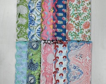 Pode incluir: Uma coleção de guardanapos de tecido estampados e coloridos com bordas onduladas. Os guardanapos apresentam desenhos florais e geométricos em tons de verde, azul, rosa e vermelho. O texto "AQSA'S" é visível.
