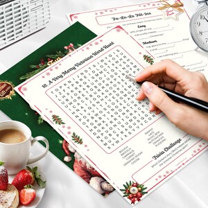Peut inclure: Image sur le th&egrave;me de No&euml;l avec des jeux de mots et des &eacute;nigmes &agrave; compl&eacute;ter, une tasse de caf&eacute; et des fraises. Une main tient un stylo pour compl&eacute;ter les &eacute;nigmes. Une radio rose et un r&eacute;veil argent&eacute; sont &eacute;galement visibles.