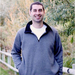 May include: A grey fleece pullover with a black collar and zipper. The zipper has a silver pull. The sweater has a kangaroo pocket.