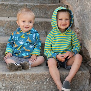 May include: Two young boys wearing hooded sweatshirts. The boy on the left is wearing a blue sweatshirt with a yellow and white construction vehicle pattern. The boy on the right is wearing a blue and yellow striped sweatshirt. Both boys are sitting on a set of concrete stairs.