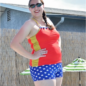 May include: A woman wearing a red and gold swimsuit top with a blue and white star print bottom. She is wearing sunglasses and has her hair in a braid.