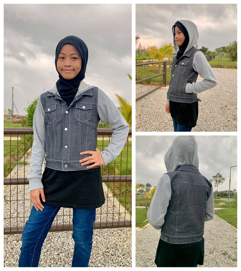 May include: A gray denim jacket with a gray hooded sweatshirt attached. The jacket has silver buttons and pockets. The person is wearing blue jeans and a black top. The background is a park with a fence.