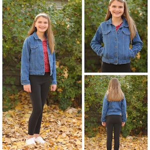 May include: A blue denim jacket with button closures, worn over a red top with white polka dots, and black leggings. The jacket has pockets and a classic collar. The outfit is completed with white sneakers. The background features autumn leaves and greenery.