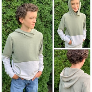 May include: A two-tone green and white long-sleeved hooded sweatshirt with a cowl neck. The sweatshirt has a pocket on the front and contrasting colour on the sleeves.