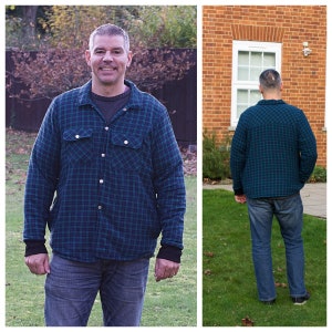May include: A man wearing a blue and green plaid flannel shirt with a button-down front and two chest pockets. He is standing in front of a green lawn.