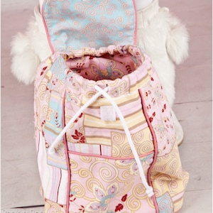 May include: A pink and blue patchwork drawstring backpack with a white drawstring and a pink lining. The backpack has a small pocket on the front.