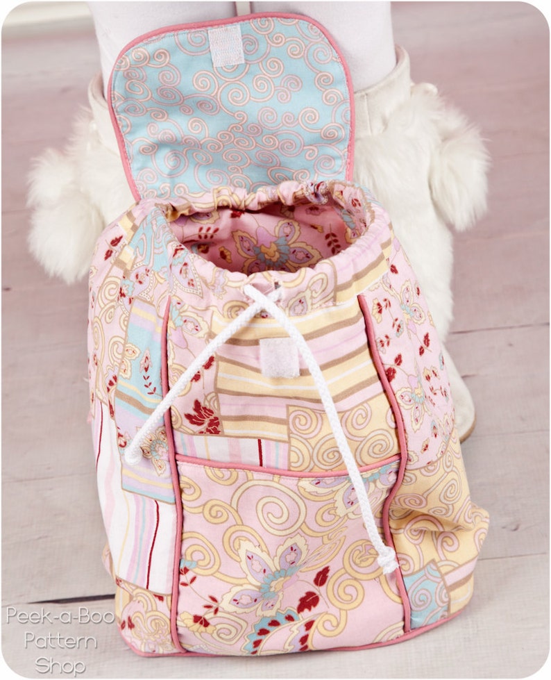 May include: A pink and blue patchwork drawstring backpack with a white drawstring and a pink lining. The backpack has a small pocket on the front.
