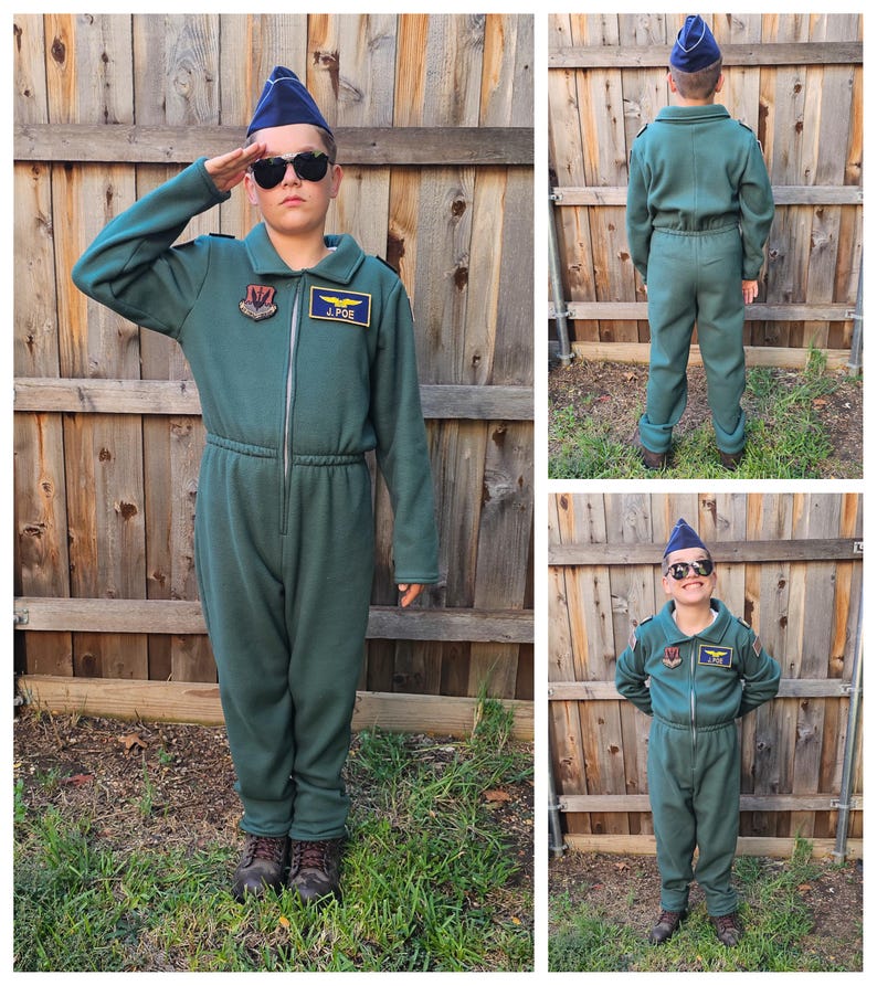 May include: A child wearing a green flight suit with a blue pilot's cap, sunglasses, and patches. The suit has a zipper and a drawstring waist. The patches include a squadron emblem and the name "J. POE".
