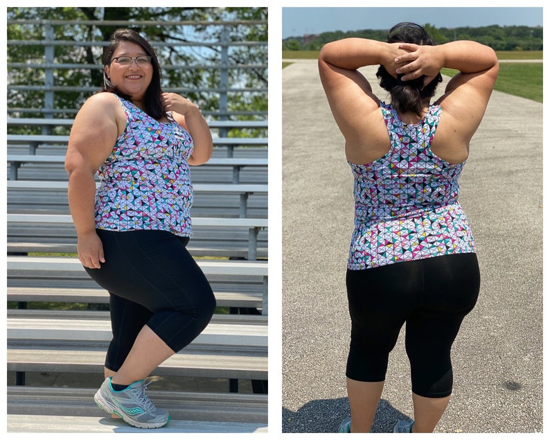 May include: A woman wearing a white tank top with a colorful geometric pattern and black capri leggings. She is standing in front of a set of bleachers.